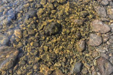 Çakıl taşlı nehir tabanı. Temiz nehir suyunun altındaki taşlar..