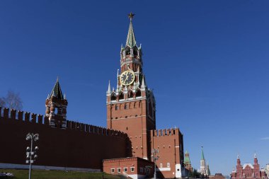 Moskova Kremlin 'in Spasskaya Kulesi. Mavi gökyüzüne karşı güneş tarafından aydınlatılmış bir saat kulesi..
