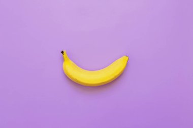 Mor neon menekşe arka plan üzerinde bir, tek muz. Metin için yer. Minimalist kavramı.