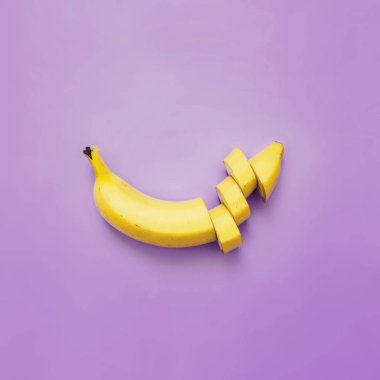 Muz, dilimleri, neon menekşe kare zemin üzerine düzenlenmiş dices kesilmiş. Metin için yer. Minimalist kavramı.