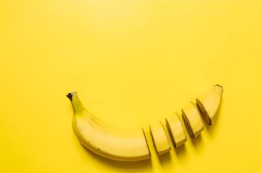Muz, dilimleri, canlı sarı yatay zemin üzerine düzenlenmiş dices kesti. Metin için yer. Minimalist kavramı.