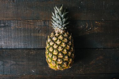 Olgun ananas koyu ahşap zemin üzerinde. Tropikal meyve yaratıcı kavramı. Alanın sığ deapth.