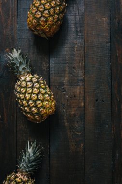 Olgun ananas koyu ahşap zemin üzerinde. Tropikal meyve yaratıcı kavramı. Kopyalama, metin, yazı için boş alan.