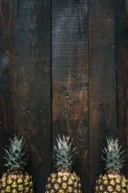 Olgun ananas sınır çerçeve koyu ahşap dikey arka plan üzerinde. Tropikal meyve yaratıcı kavramı. Kopyalama, metin, yazı için boş alan.