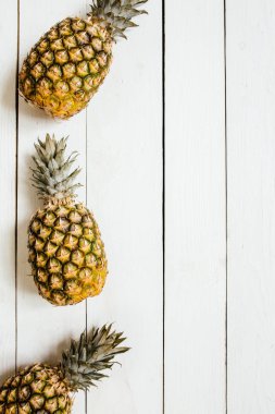 Olgun ananas sınır çerçeve beyaz ahşap zemin üzerinde. Tropikal meyve yaratıcı kavramı. Kopyalama, metin, yazı için oda.