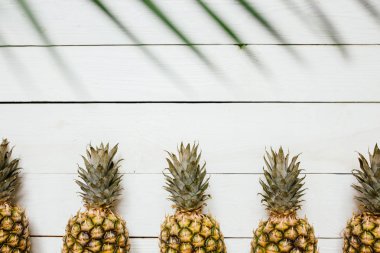 Olgun ananas sınır çerçeve beyaz ahşap zemin üzerinde. Tropikal meyve yaratıcı kavramı. Kopyalama, metin, yazı için oda.