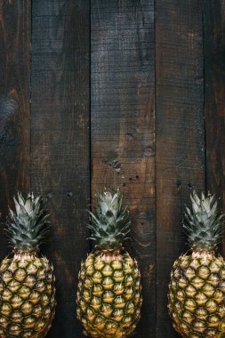 Olgun ananas sınır çerçeve koyu ahşap dikey arka plan üzerinde. Tropikal meyve yaratıcı kavramı. Kopyalama, metin, yazı için boş alan.