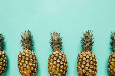 Olgun ananas sınır çerçeve izole turkuaz arka plan üzerinde. Minimalist tarzı moda tropikal kavramı. Metin, kopyalama, yazı için boş alan.