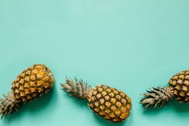 Olgun ananas sınır çerçeve izole turkuaz arka plan üzerinde. Minimalist tarzı moda tropikal kavramı. Metin, kopyalama, yazı için boş alan.