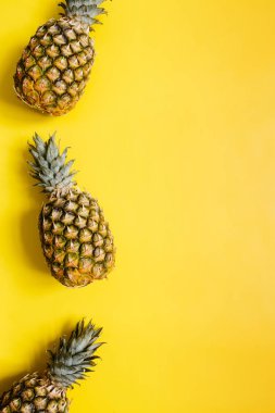 Olgun ananas sınır çerçeve izole canlı sarı zemin üzerine. Minimalist tarzı moda tropikal kavramı. Metin, kopyalama, yazı için boş alan.
