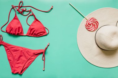 Kırmızı, pembe bikini takım, lolipop, düz ışık mavi zemin üzerine beyaz şapka. Kopyalama, metin, yazı için boş alanı. Yaz tatil kavramı. Poster, afiş, kartpostal şablonu.