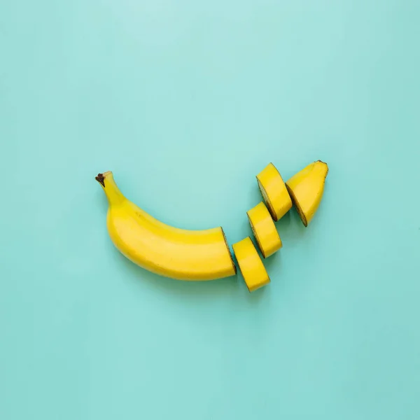 Cut banana, slices, dices arranged on square cyan green, blue, ultramarine background. Room for text. Minimalist concept.