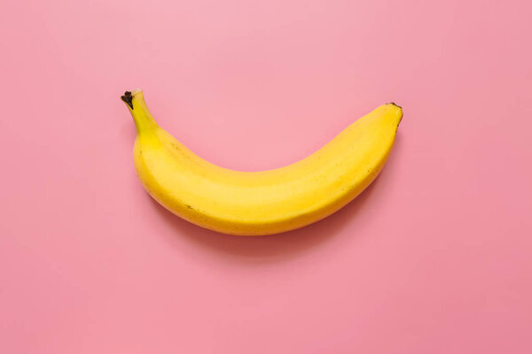 One, single banana on pink background. Room for text. Minimalist concept.