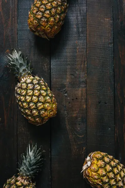 Olgun ananas koyu ahşap zemin üzerinde. Tropikal meyve yaratıcı kavramı. Kopyalama, metin, yazı için boş alan.