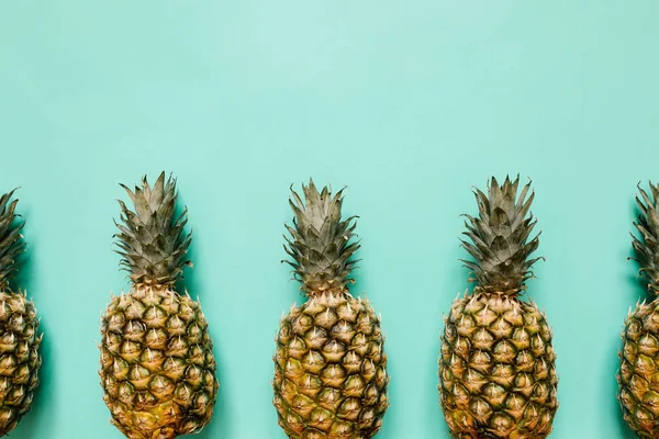 Olgun ananas sınır çerçeve izole turkuaz arka plan üzerinde. Minimalist tarzı moda tropikal kavramı. Metin, kopyalama, yazı için boş alan.