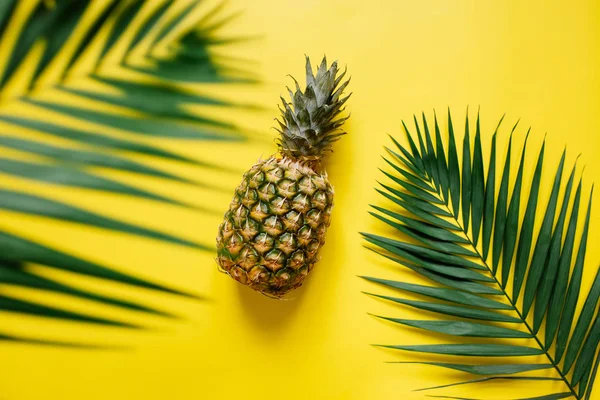 Olgun ananas izole canlı sarı zemin üzerine. Palm kenarlık çerçeve bırakır. Minimalist tarzı moda tropikal kavramı. Metin, kopyalama, yazı için oda.