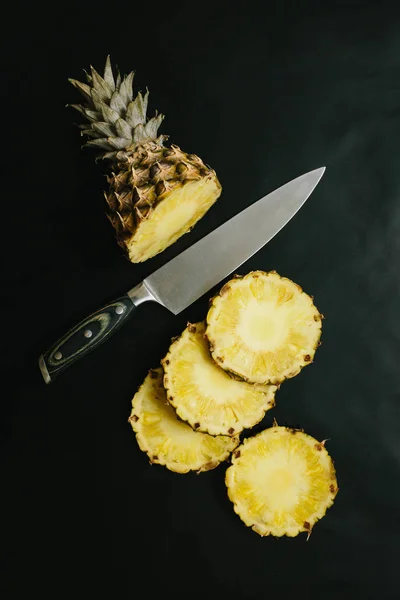 Sliced ripe pineapple on concrete black table countertop plain background. Healthy nutrition food concept.