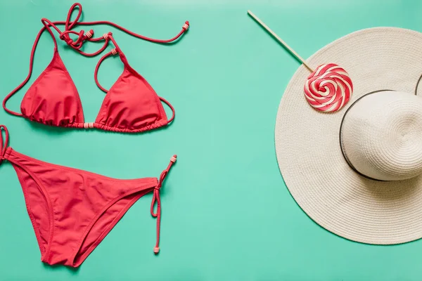 Kırmızı, pembe bikini takım, lolipop, düz ışık mavi zemin üzerine beyaz şapka. Kopyalama, metin, yazı için boş alanı. Yaz tatil kavramı. Poster, afiş, kartpostal şablonu.