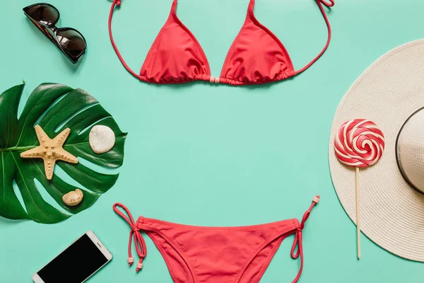 Kırmızı, pembe bikini takım, lolipop, güneş gözlüğü, smartphone, düz açık mavi renkli şapka. Kopyalama, metin, yazı için boş alanı. Yaz tatil kavramı. Poster, afiş, kartpostal şablonu.
