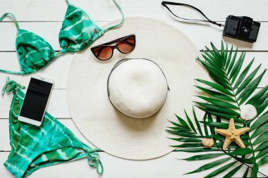 Bikini takım elbise, şapka, güneş gözlüğü, film kamerası, smartphone, deniz yıldız, yeşil plam ahşap baclground görücü usulü bırakır. Yaz tatil tatil kavramı. Poster afiş, kartpostal şablonu.