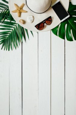 Şapka, güneş gözlüğü, smartphone, deniz yıldız, yeşil plam ahşap baclground görücü usulü bırakır. Yaz tatil tatil kavramı. Poster afiş, kartpostal şablonu.