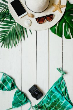 Bikini takım elbise, şapka, güneş gözlüğü, film kamerası, smartphone, deniz yıldız, yeşil plam ahşap baclground görücü usulü bırakır. Yaz tatil tatil kavramı. Dikey afiş, kartpostal şablonu.