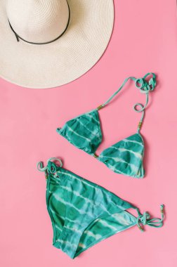 Akuamarin bikini mayo ve hasır şapka açık pembe renkli düzenlenmiştir. Minimalist tarzı yaratıcı kavramı.