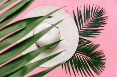 Beyaz hasır şapka ve yeşil palmiye üzerinde görücü usulü açık pembe renkli bırakır. Minimalist tarzı yaz tatil kavramı. Kopyalama, metin, yazı için boş alan.