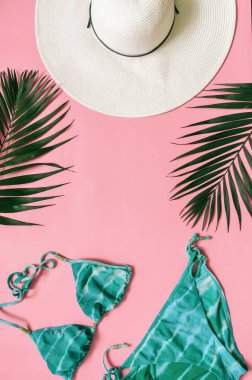 Plaj giyim ve tropikal yaprak, pembe arka plan düzenlenmiştir. Yaz tatil minimalist tarzda kavramı.