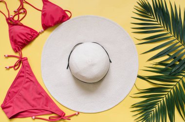 Plaj giyim ve tropikal yaprak sarı zemin üzerine düzenlenmiştir. Yaz tatil minimalist tarzda kavramı.