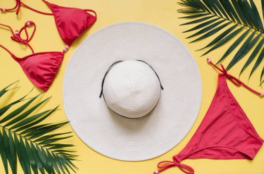 Plaj giyim ve tropikal yaprak sarı zemin üzerine düzenlenmiştir. Yaz tatil minimalist tarzda kavramı.