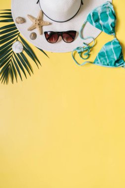 Plaj giyim ve tropikal yaprak sarı zemin üzerine düzenlenmiştir. Yaz tatil minimalist tarzda kavramı.