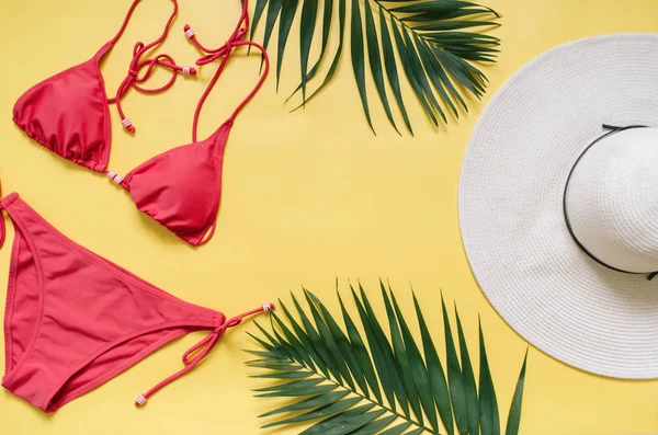 Plaj giyim ve tropikal yaprak sarı zemin üzerine düzenlenmiştir. Yaz tatil minimalist tarzda kavramı.