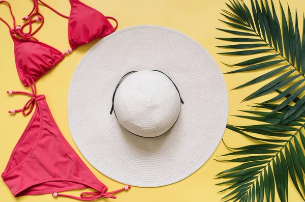 Plaj giyim ve tropikal yaprak sarı zemin üzerine düzenlenmiştir. Yaz tatil minimalist tarzda kavramı.