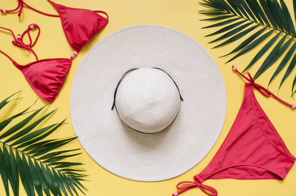 Plaj giyim ve tropikal yaprak sarı zemin üzerine düzenlenmiştir. Yaz tatil minimalist tarzda kavramı.