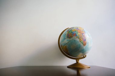 Koyu ahşap masa üzerinde küre modeli. Beyaz duvar boş alan arka plan.