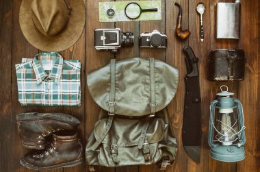 Orman tropik orman, ahşap zemin üzerinde düzenlenmiş şeyler hiking dağlar. Pala, gömlek, giyim, çizmeler, fener, Sigara boru, şapka, harita, pusula. Trekking kartpostal, poster, afiş kavramı.