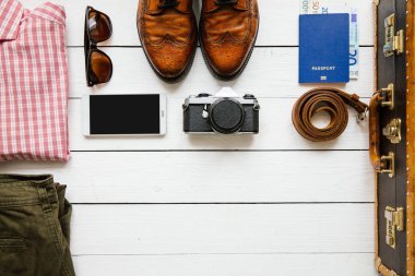 Vintage hipster giysi, Ayakkabı, şapka, smartphone, aksesuar, çanta ambalaj önce beyaz tahta masada. Seyahat kavramı. Kopyalama, metin, yazı için boş alan.