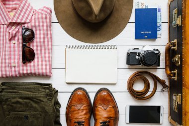 Vintage hipster giysi, Ayakkabı, şapka, smartphone, aksesuar, çanta ambalaj önce beyaz tahta masada. Seyahat kavramı. Kopyalama, metin, yazı için boş alan.
