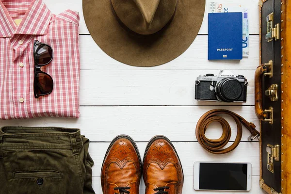 Vintage hipster giysi, Ayakkabı, şapka, smartphone, aksesuar, çanta ambalaj önce beyaz tahta masada. Seyahat kavramı. Kopyalama, metin, yazı için boş alan.