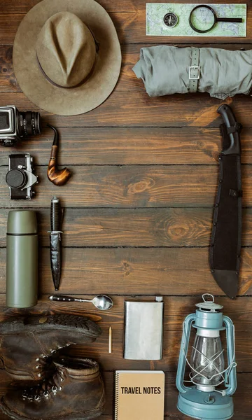 Camping gear including knife, clothes, boots, lantern, camera, hat, map, compass. Vertical wanderlust, safari postcard, poster, banner template. Room for text,copy, lettering.