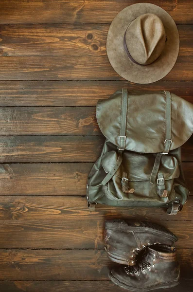 Jungle tropical forest, mountains hiking stuff arranged on wooden floor. Backpack, hat, boots. Safari concept. Empty space for copy,text, lettering.