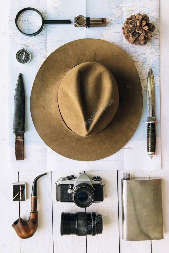 Adventure planning flat lay. Travel vintage gear on map. Including film camera, hat, knife, loupe, compass. Exploring, hiking empty space poster, postcard concept.