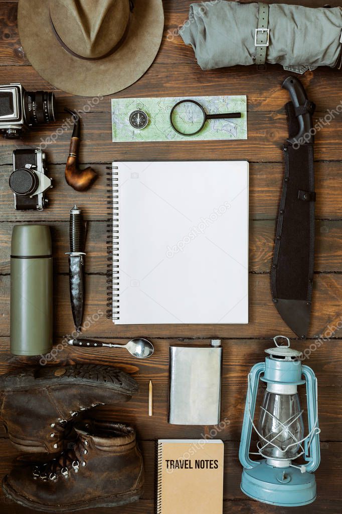 Camping gear including knife, clothes, boots, lantern, camera, hat, map, compass. Vertical wanderlust, safari postcard, poster, banner template. Empty notepad space for text,copy, lettering.