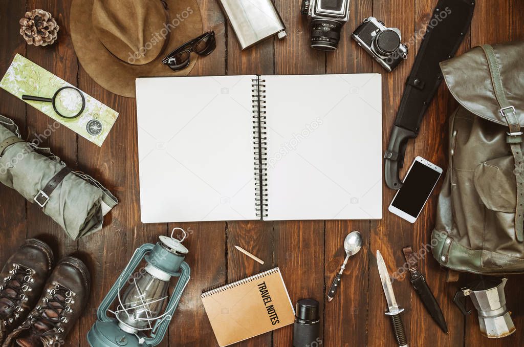 Mountains hiking stuff arranged on wooden floor. Machete, boots, lantern, camera, hat, map, compass. Copy space. Camping concept. Safari postcard, poster, banner template.