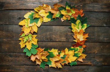 Sonbahar sarı kırmızı yeşil çelenk koyu kahverengi ahır ahşap plakalar arka plan üzerinde yapraklar. Yatay kartpostal şablonu. Kopyalama, metin, yazı için boş alan.