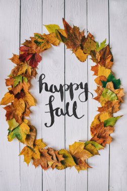 Mutlu Güz el yazısıyla yazılmış modern hat üzerinde renkli sonbahar kuru oval çelenk çerçeve beyaz boyalı rustik ahır ahşap boşlukları arka plan üzerinde bırakır. Dikey kartpostal.