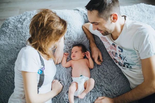 Mutlu bir aile. Genç Anne ile aralarındaki küçük yeni doğan bebek yatakta yalan.