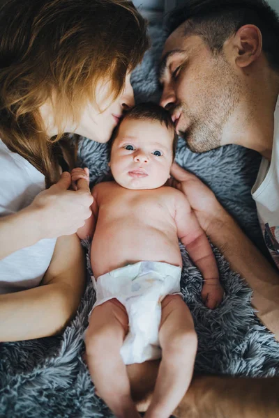 Mutlu bir aile. Sevimli küçük yeni doğan bebek öpüşme yatakta yatan anne. Portre portre.