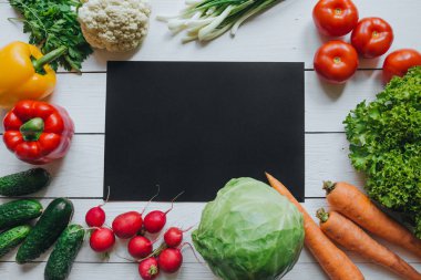 Sağlıklı gıda kavramı. Sebze salatası malzemeler sınır çerçeve. Beyaz ahşap masa boş alan arka plan siyah kağıda. Organik poster düz lay şablon.